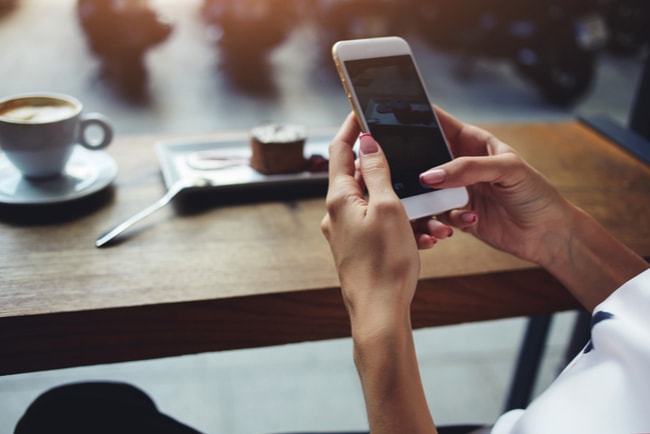 Kvinna på café använder sin mobiltelefon